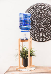 Beautiful Timber Stand with Hi Vibe Ceramic placed on top, water on ceramic.  litre water bottles next to the stand. A plant is on the base of the stand with a beautiful mandala in the background. 