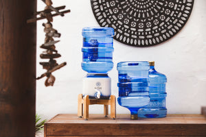 Beautiful Timber Stand with hi vibe ceramic and water bottle on top and 2 15 litre hi vibe water bottles next to it with a mandala in the background 